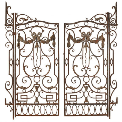 Pair of French circa 1890 wrought iron gates with forged and hammered scrollwork, central gilt laurel swag suspended from ribbon bow, acanthus volutes, and two-tone rust and gilt patina, 33¾ by 73¾ inches each